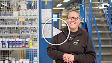 Lagerchef Stine står foran lager. Afspilnings icon foran for at vise, det er en video