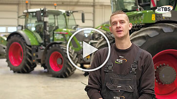Medarbejder hos TBS foran Fendt traktorer. Afspilnings icon henover for at vise det er en video.