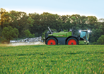Fendt Rogator sprøjter på mark ved siden af skov
