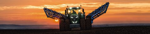 Fendt traktor kører med sprøjte på en mark ved solnedgang